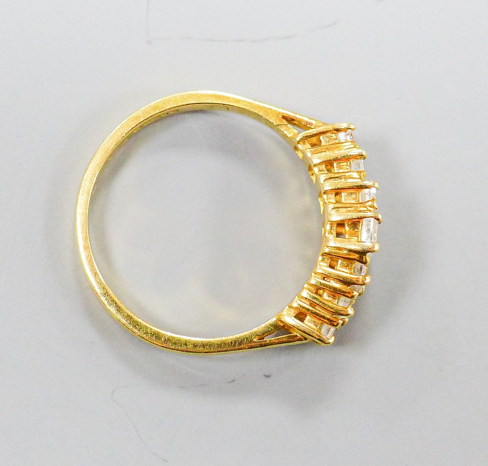 A modern 18ct gold and graduated seven stone baguette cut diamond set half hoop ring, size O, gross weight 4.1 grams.